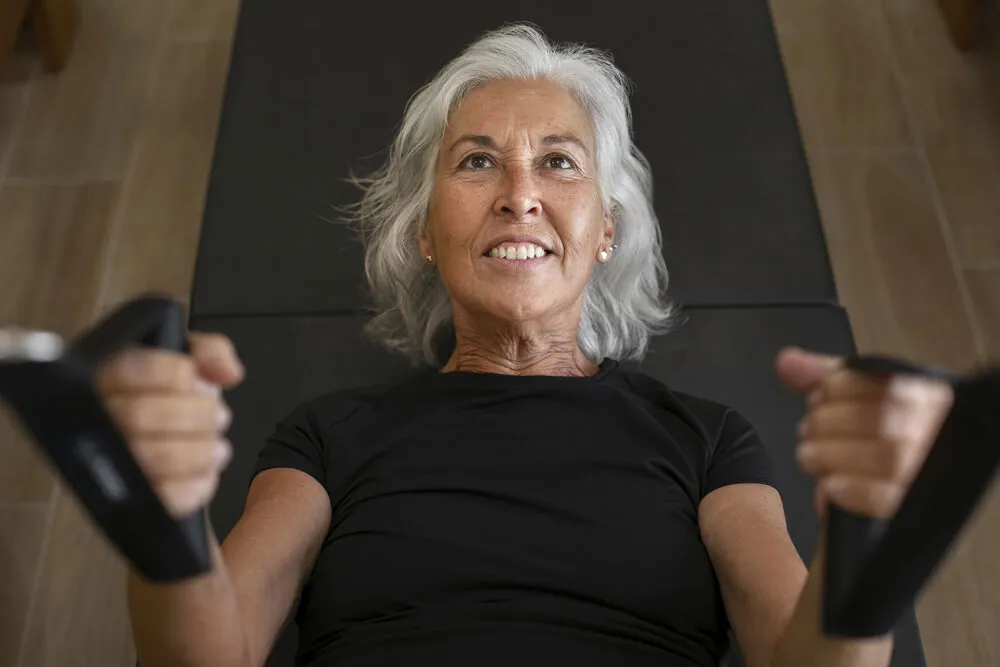 Mulher sorrindo durante exercício de pilates